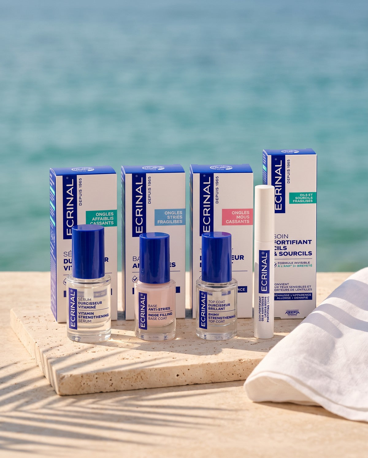 Ecrinal vitamin nail strengthener, ridge-filling base coat, shiny top coat and lash and brow gel on travertine by the sea